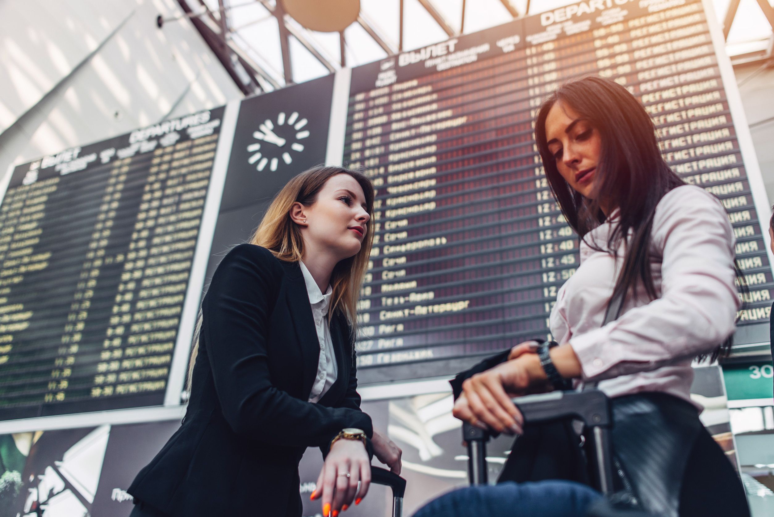 Two Female Tourists Standing Near Flight Information